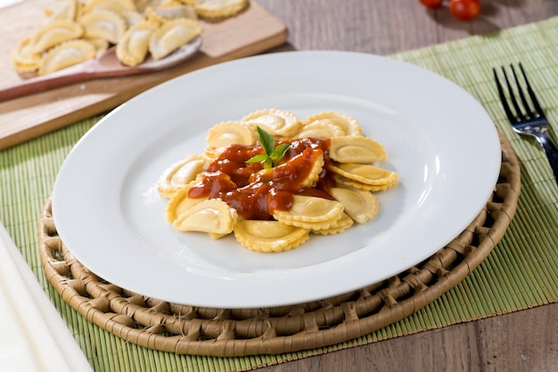 Pasta Ravioli op wit bord met cherrytomaatjes op de achtergrond