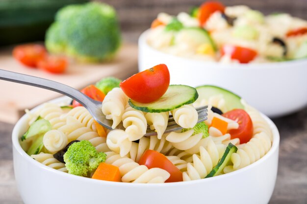 Pasta salad in a bowl on a rustic wooden table