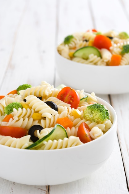 Pasta salad in a bowl on white wood table