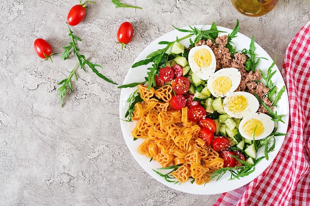 Insalata di pasta con verdure fresche, uova e tonno in una ciotola bianca. pranzo vista dall'alto. disteso