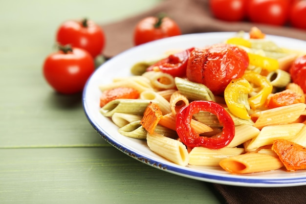 Pasta salad with pepper carrot and tomatoes on wooden table background