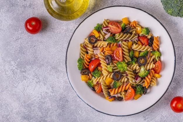 Pasta salad with tomato, broccoli, black olives. Top view