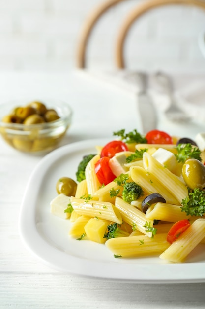 Pasta salad with tomatoes and olive on wooden table