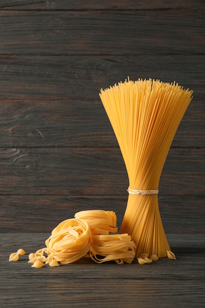 Pasta samenstelling op houten tafel, ruimte voor tekst. Droge rauwe hele pasta