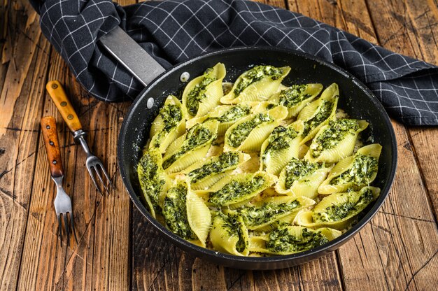 Pasta schelpen Conchiglioni gevuld met spinazie en kaas gebakken met saus in een pan