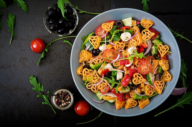 Pasta in the shape heart salad with tomatoes, cucumbers, olives, mozzarella and red onion