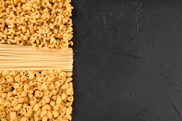 Pasta and spaghetti on black background copy space