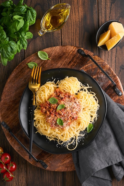 Pasta spaghetti Bolognese Lekkere smakelijke Italiaanse spaghetti met bolognese saus tomatensaus kaas Parmezaanse kaas en basilicum op witte plaat op oude houten rustieke tafel achtergrond Bovenaanzicht