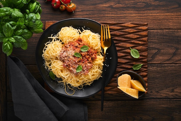 Pasta spaghetti bolognese tasty appetizing italian spaghetti
with bolognese sauce tomato sauce cheese parmesan and basil on
white plate on old wooden rustic table background top view