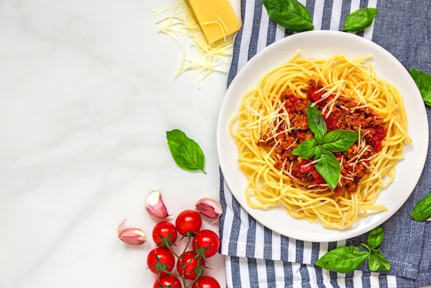 Spaghetti della pasta bolognese su un piatto bianco sull'asciugamano di cucina sopra la tavola di marmo bianca. cibo salutare. vista dall'alto