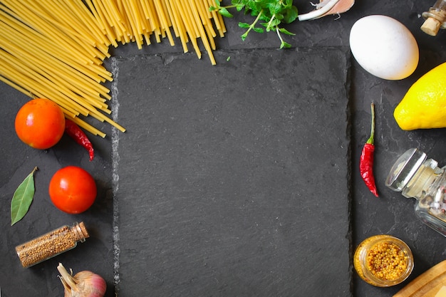 パスタ、スパゲッティまたはブカティーニとトマトソースの材料。食品の背景。コピースペース