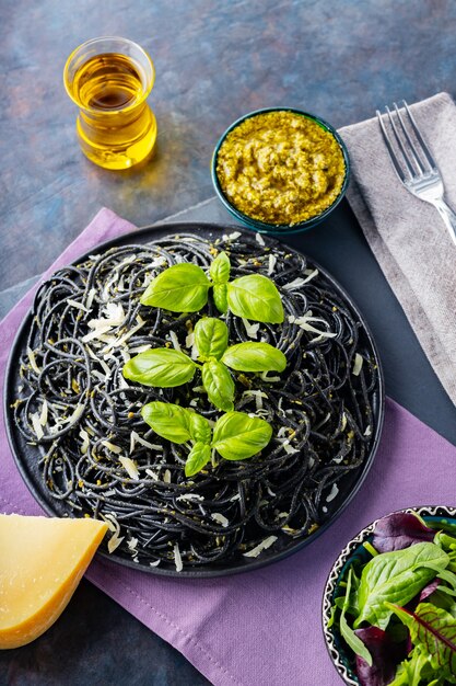 Pasta spaghetti met Parmezaanse kaas, basilicum en pestosaus. Zwarte pasta met inktvisinkt