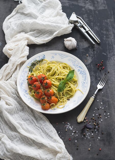 Pasta spaghetti met pestosaus basilicum gebakken cherrytomaatjes op rustieke houten tabke donkere tafel bovenaanzicht