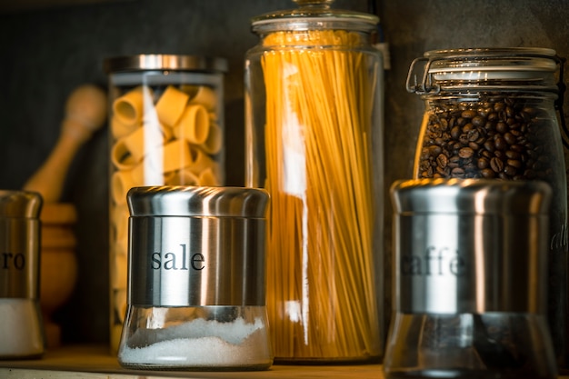 pasta, spaghetti, sugar, salt and coffee in different containers on the shelf
