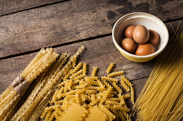 Макаронные изделия спагетти с яйцом на старой деревянной поверхности