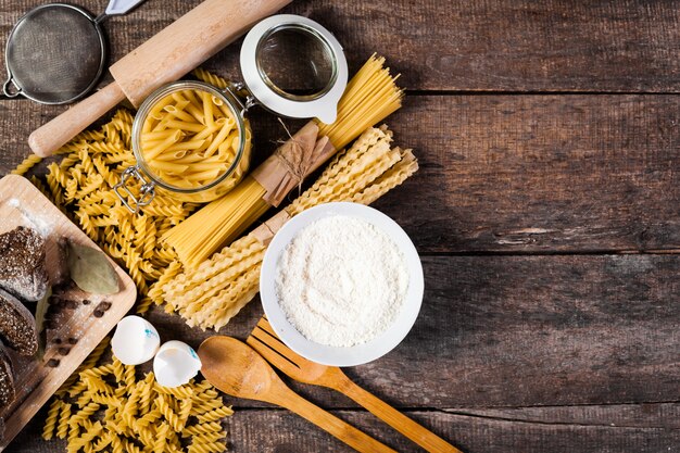 Pasta spaghetti with flour, egg on old wooden 