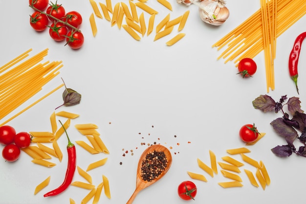 Foto spaghetti della pasta con gli ingredienti per la cottura della pasta su un fondo bianco, vista superiore.