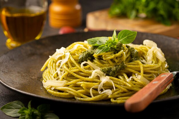 Pasta spaghetti with pesto sauce and basil leaf.