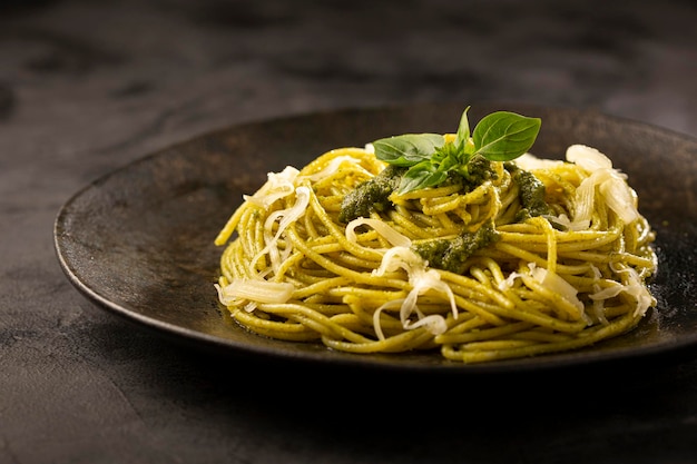 Паста спагетти с соусом песто и листом базилика.