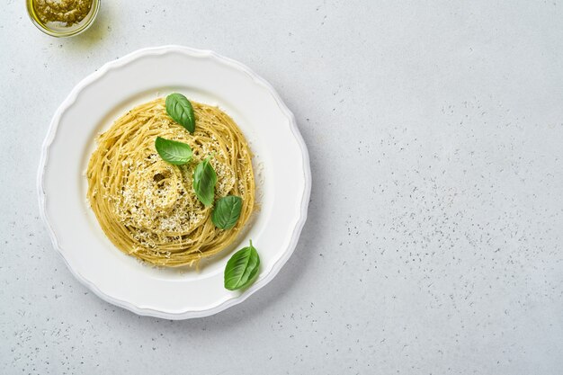 паста спагетти с соусом песто и свежими листьями базилика в белой миске