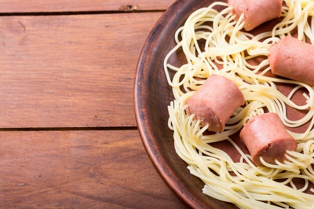 Foto spaghetti con salsiccia su fondo rustico