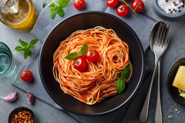 Foto pasta, spaghetti con salsa di pomodoro in ciotola nera. vista dall'alto.