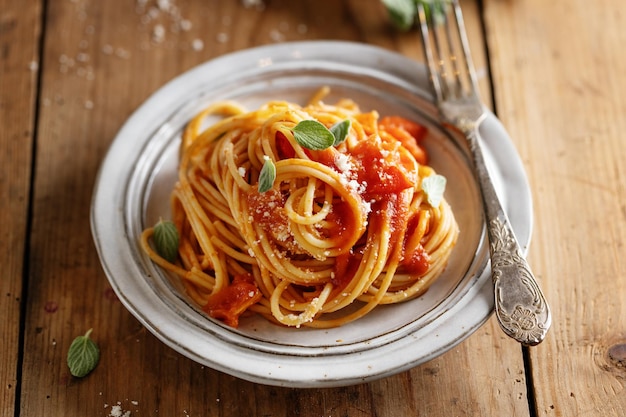 Spaghetti di pasta con salsa di pomodoro e formaggio serviti sul piatto.