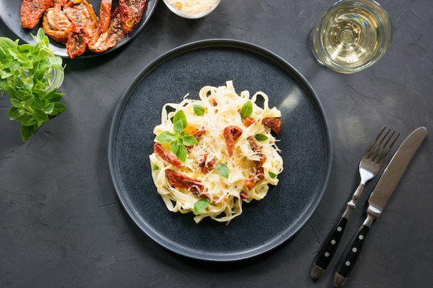 Pasta tagliatelle met gedroogde tomaten en oregano op zwart. Heerlijke mediterrane lunch.