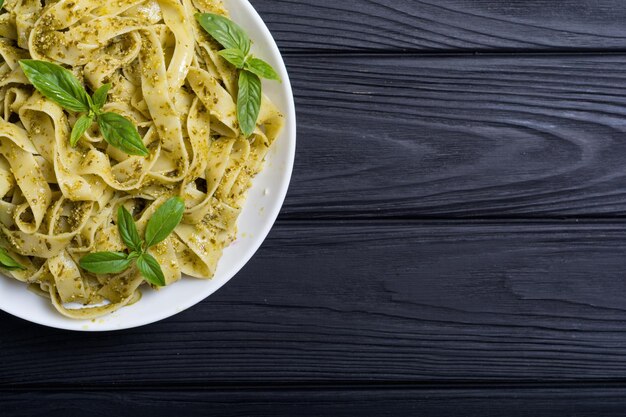 Pasta tagliatelle with green sauce pesto Italian food background