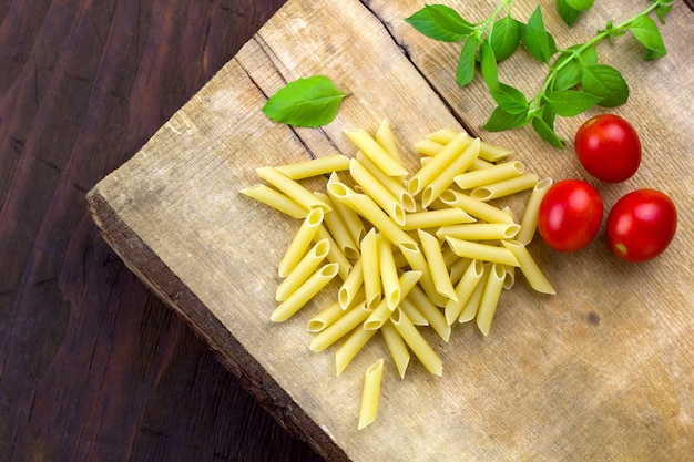 Pasta, tomaten, basilicum op een houten snijplank