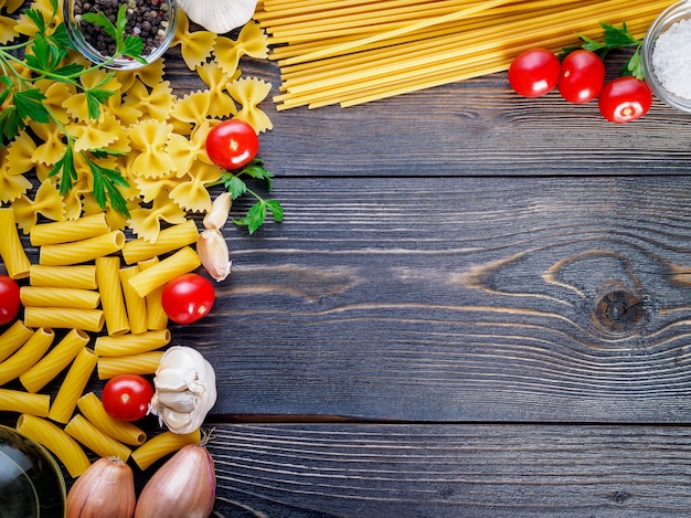 Pasta, tomaten, sjalotten, knoflook, peterselie op donkere houten achtergrond