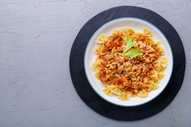 Pasta in tomato bolognese sauce on a black stand on a concrete background. copy space Horizontal photo