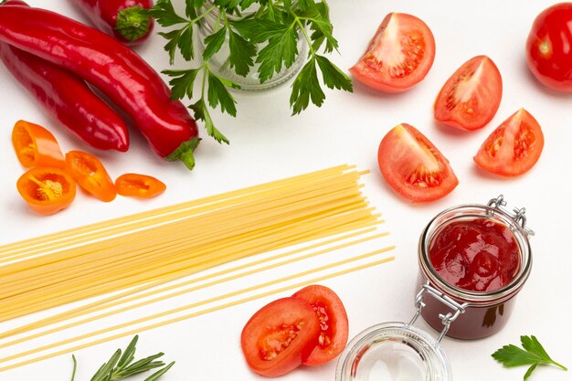 Pasta and tomato halves. Tomato sauce in jar. White background. Top view