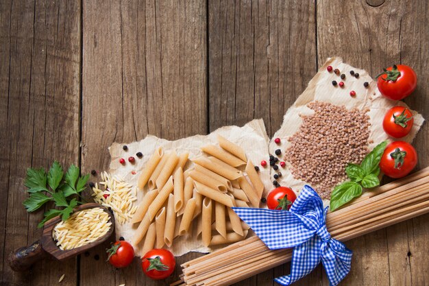 Pasta, tomatoes and basil on wooden background top view with copy space