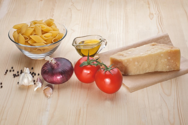 Photo pasta, tomatoes, cheese, garlic on table