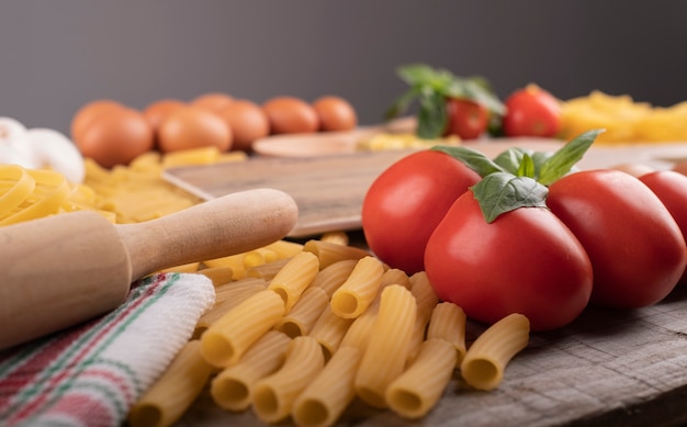 Pasta, tomatoes and ingredients for italian restaurant with wooden kneader