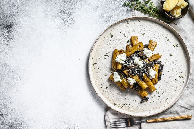 Pasta tortiglioni met zwarte truffel en Boletus edulis, witte champignon. Grijze achtergrond. Bovenaanzicht. Ruimte voor tekst