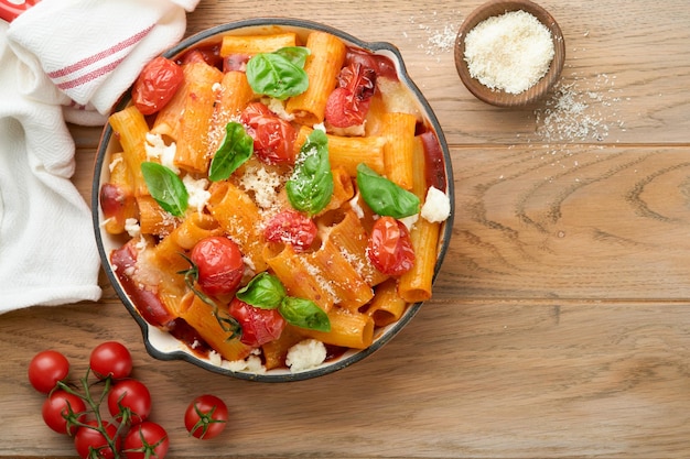 Pasta Tortiglioni with tomato sauce baked cherry tomatoes mozzarella and parmesan cheese basil on old rustic table background Traditional Italian cuisine Example Italian food for article Top view