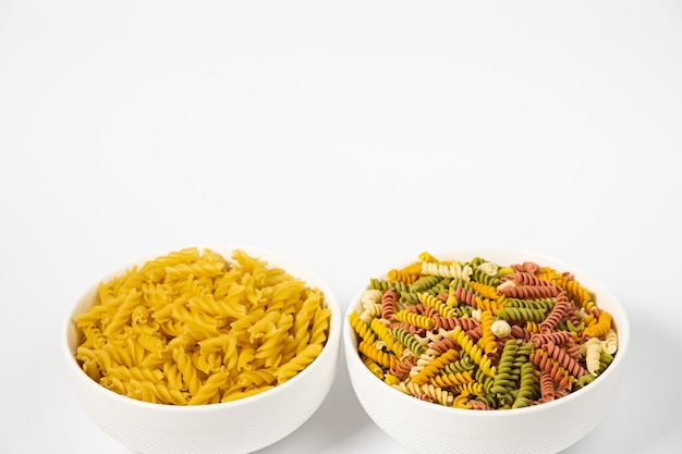 Pasta trottole tricolore tarwe in een bord geïsoleerd op een witte achtergrond