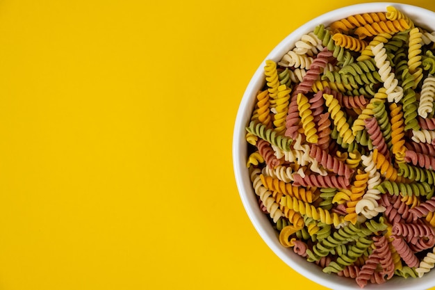 Pasta trottole tricolore wheat in a plate isolated on yellow background