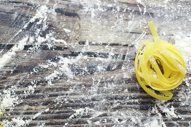 Foto pasta cruda sul tavolo. tagliatelle sotto forma di nidi. farina e condimenti.