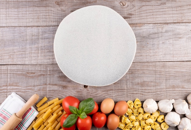 Pasta, vegetables, eggs, with dish in the middle on wooden board