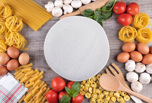 Pasta, vegetables, eggs, with dish in the middle on wooden board