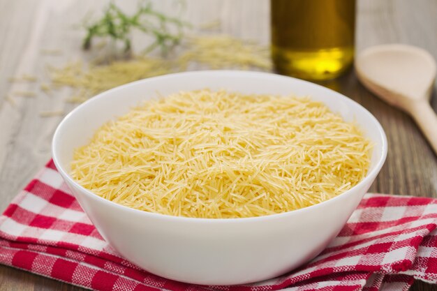 Pasta on white bowl on napkin on brown wood