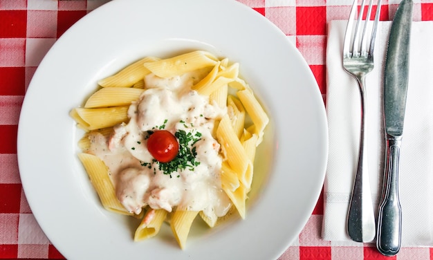 Foto pasta in salsa bianca e guarnizione di pomodoro ciliegino