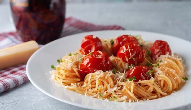 Pasta with baked tomatoes parmesan and microgreens