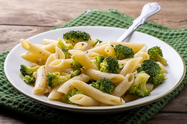 Pasta con i broccoli su un piatto bianco e una tavola di legno