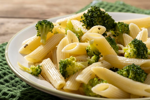 Pasta con i broccoli su un piatto bianco e una tavola di legno Foto Premium