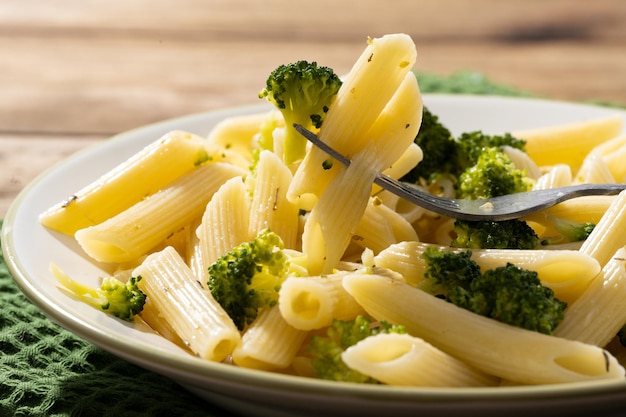 Pasta with broccoli on a white plate and wooden table