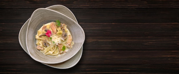 Pasta with cheese mushrooms and chicken on a wooden background